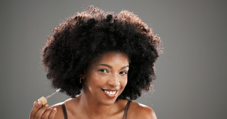 Skincare, portrait and woman with serum in studio for wrinkle treatment, hydration or natural beauty. Mockup, African person and happy with cosmetics dropper for skin regeneration on gray backgroundの写真素材