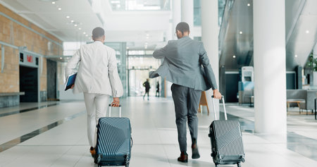 Businessmen, walking and travel with suitcase for corporate commute or job opportunity at airport. Back view, male people or employees with luggage for career immigration, business trip or journeyの写真素材