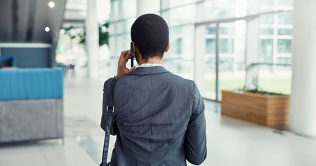 Back, phone call and black woman in office, communication or feedback for inflation analysis. African person, employee or financial advisor in hallway, cellphone or conversation with app for chattingの写真素材