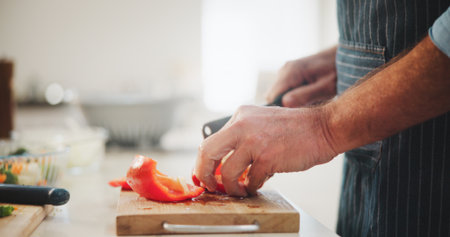 Peppers, hands and man cutting vegetables in home for cooking healthy dinner, meal or supper for diet. Knife, groceries and chef chop fresh ingredients for wellness, nutrition or recipe in kitchen.の写真素材