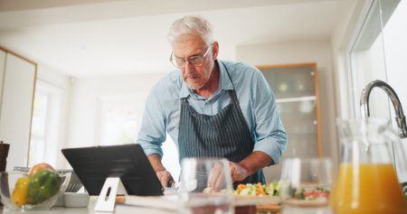 Learning, senior or man with tablet for cooking recipe tutorial, lunch and guide in home. Kitchen, retirement or elderly person reading blog for ingredients instruction, food diet or meal prep stepsの写真素材