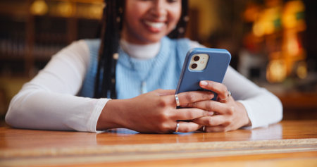 Hands, phone and texting with app at coffee shop with contact, typing or streaming on web at restaurant. Person, smartphone and click with chat, search and smile with social media at cafeteriaの写真素材