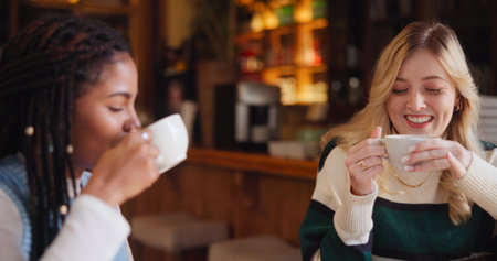 Coffee shop, happy and women with drink in conversation for hangout, reunion and bonding. Restaurant, cafe and people with beverage, talking and gossip for relaxing, social chat and friendshipの写真素材