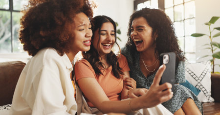 Selfie, laughing and relax with friends on sofa for support, bonding and social media together. Post update, smile and connection with women in living room of home for love, reunion and video callの写真素材
