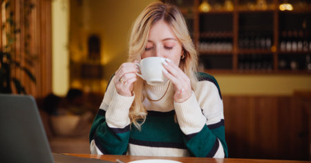Woman, student and drink with coffee cup at shop for study, project and break with beverage at diner. Girl, person and computer with tea, caffeine or latte for scholarship in morning at cafeteriaの写真素材