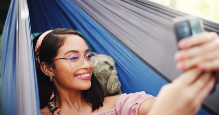 Happy, tourist and woman on hammock, selfie and photography for summer vacation, outdoor and travel. Relax, traveller and person with smile for profile picture, post and memory for holiday or tripの写真素材
