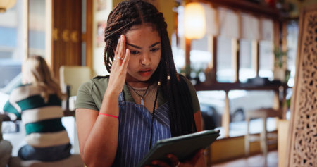 Woman, barista and headache with stress at coffee shop, pain and mistake with inventory checklist. Person, waitress or server with tech, application or burnout with migraine, glitch or tired at cafeの写真素材