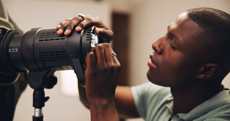 Photographer, man or lighting setup in studio for photoshoot preparation, production or flashlight. Behind the scenes, photography and black person with equipment setting for spotlight and backstageの写真素材