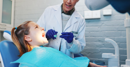 Consulting, dentist and child with woman in office for oral hygiene, healthcare and mouth. Teeth cleaning, medical and orthodontist appointment with kid and person in dental clinic for treatmentの写真素材