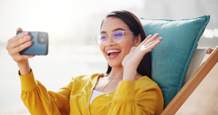 Business woman, video call and outdoor for wave, networking and speaking with contact. Technology, cellphone and female consultant with hello for vacation, talking and conversation with hand gestureの写真素材