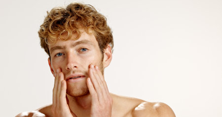 Facial, portrait and skincare with man in studio for grooming, hygiene or wellness routine. Beauty, cosmetics and lotion with person on white background to apply face cream or moisturizer on spaceの写真素材