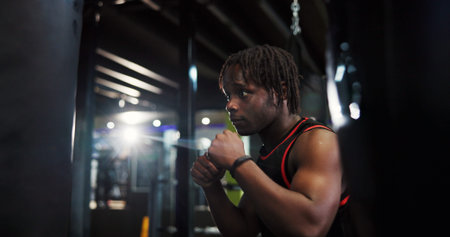 Black man, punching bag and boxing for fitness at gym with power, challenge or martial arts. African...