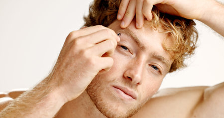 Portrait, man and tweezers in studio for hair removal, beauty maintenance and skincare routine. Male...