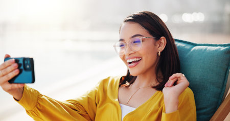 Business woman, video call and outdoor for smile, networking and speaking with contact. Technology, cellphone and female consultant with hello for vacation, talking and conversation with hand gestureの写真素材