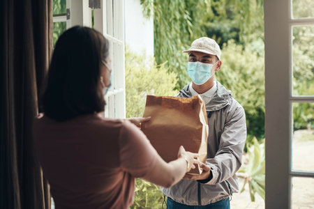 Delivery man, package and woman with mask in home with ocd or germ protection, health and anxiety for bacteria. Female person, logistics and professional courier service for customer care and safetyの写真素材