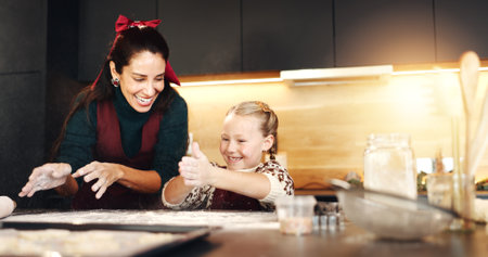 Christmas, baking and smile of mother with daughter in kitchen of home for bonding or celebration. Flour, ingredients or recipe with happy parent and girl child in apartment for festive cookingの写真素材