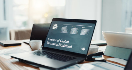 Global warming, screen and laptop on desk in office for website, information and research. Business, empty and computer with online article for environmental causes, climate change and conservationの写真素材