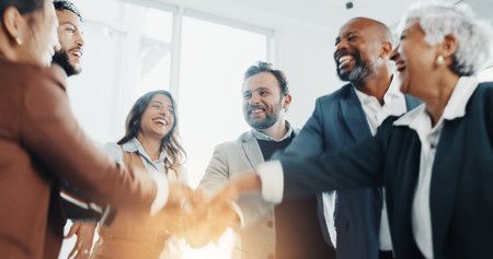 Business people, laugh and hands together in huddle for goal, collaboration or corporate target. Smile, mission or group of employees in celebration for partnership, teamwork or success in officeの写真素材