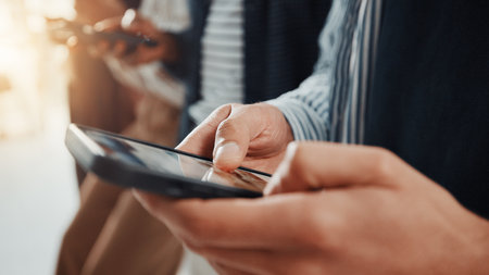 Business people, hands and typing with phone in waiting room for career search or job research. Closeup, group or employees browsing with mobile smartphone in line or row for interview in workplaceの写真素材