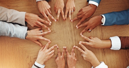 Peace sign, hands and business people in office for teamwork, agreement and partnership. Professional, corporate and above of workers for collaboration, support and coworking synergy on deskの写真素材