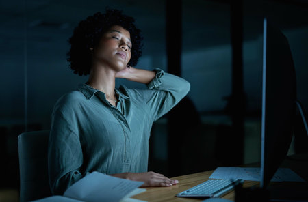 Wheres a massaging chair when you need one. Shot of a young businesswoman experiencing neck pain while using a computer during a late night at work.の写真素材
