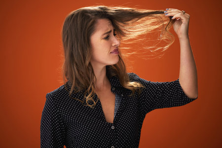 Confused, sad and hair loss of woman, studio and stress with worry, fragile and texture of hairdo. Red background, mockup and girl with hereditary of baldness, fear and unhappy with haircare in salonの写真素材
