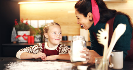 Christmas, baking or flour with mother and daughter in kitchen for December holiday season. Celebration, having fun and smile of girl child with happy single parent in home for festive cookingの写真素材