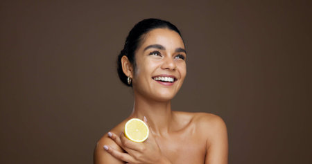 Happy woman, lemon or skincare with vitamin C in studio for detox on a brown background. Female person, model or smile with natural organic fruit or diet for citrus acid, health and collagen on spaceの写真素材