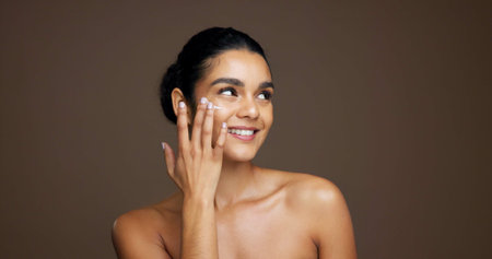 Thinking, woman and happy with cream, skincare or cosmetics for smooth skin, shine and mockup space. Studio background, reflection and person with smile for beauty, dermatology and facial treatmentの写真素材
