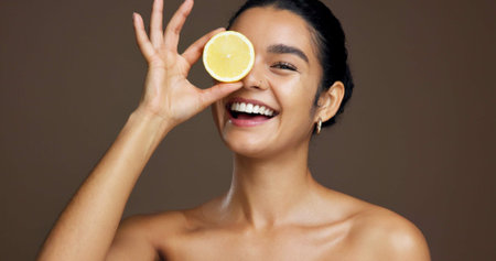 Happy woman, portrait or lemon with vitamin C in studio for skincare detox on a brown background. Face, female person or model with smile or natural organic fruit for citrus acid, health and collagenの写真素材