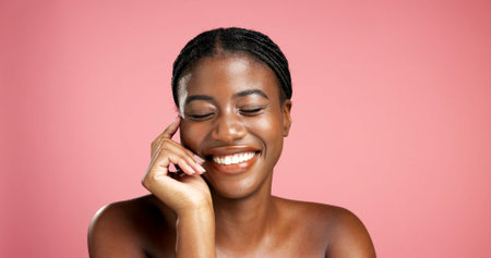 Space, laughing or black woman in studio with smile, wellness and skincare for satisfaction. Shine, happy or funny African person isolated on pink background with confidence, beauty and cosmeticsの写真素材