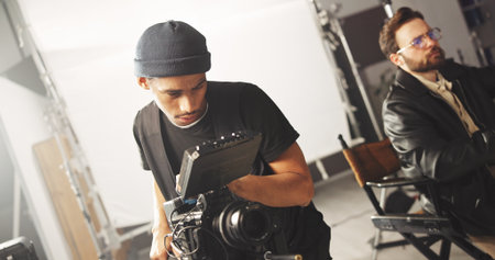 Film, production and videography with cameraman on set for cinematic recording of footage. Art, behind the scenes or media with director and videographer in studio for cinematography or shoot processの写真素材