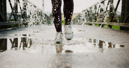 Exercise, puddle and shoes running with splash on bridge for endurance, winter workout or sports. Fitness, legs and person with cardio outdoor for race performance, marathon competition and challengeの写真素材