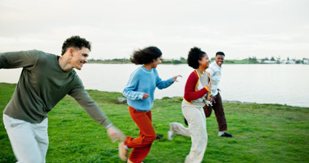 Holiday, friends and running outdoor at lake for bonding, excited students and adventure together. Man, woman and group race on vacation for travel, journey and happy with energy on gap year by parkの写真素材