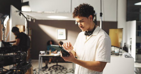 Man, producer and tablet for filming backstage for editing video, review script and shooting catalog. Male director, digital app and checklist, scene footage and performance guide of movie productionの写真素材