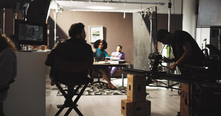 Production, man and director in studio with back view for film, shooting movie and media on set. Behind the scenes, people and camera crew for direction, videography and recording for cinematographyの写真素材