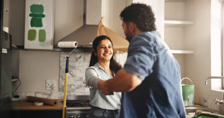 Dance, DIY and painting with couple in kitchen of apartment together for home improvement. Celebration, music and renovation with people in new house for maintenance, remodeling or restorationの写真素材