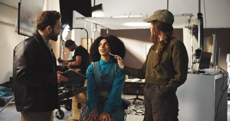 Director, actress and makeup artist with production crew for instructions or preparation on set....