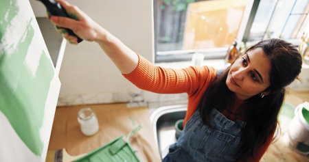 Above, woman and painting kitchen at new house for renovation, interior design and decoration. Female person, furniture and paint brush for diy improvement, remodeling process and repairs maintenanceの写真素材