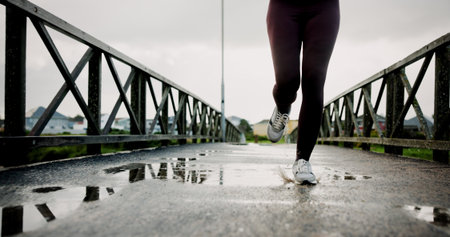 Workout, legs and athlete running on bridge for pace training, winter exercise or resilience. Fitness, shoes or person with cardio outdoor for endurance challenge, marathon competition or performanceの写真素材