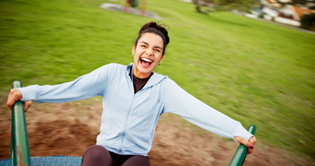 Woman, laughing and spinning on roundabout at playground for workout break, adrenaline and portrait. Fitness, POV and excited person on merry go round at park for playing, freedom and amusement rideの写真素材