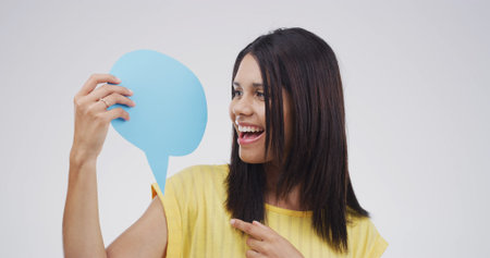 Woman, smile and point with speech bubble, studio or choice with mockup space by white background....