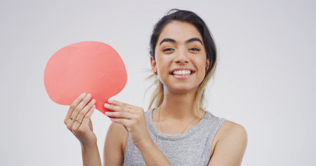 Portrait, happy woman and speech bubble with sign for voice, language and idea. Smile, person and dialogue balloon for opinion, feedback and translation on white studio background with mockup spaceの写真素材