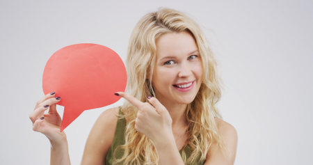 Happy woman, speech bubble and point in studio, portrait and mock up space on white background. Person, smile and blank poster for feedback, announcement and choice with social media in Germanyの写真素材