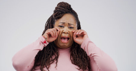 Sad, black woman or portrait with cry for emotional breakup on a white studio background. Female person, tears and model with sob, stress or expression for divorce, mental health or bad news on spaceの写真素材