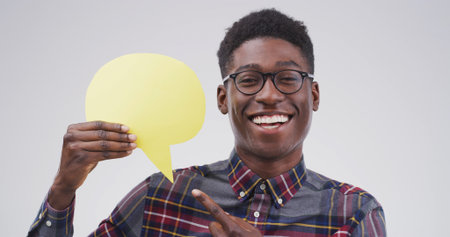 Black man, speech bubble and point in studio portrait with mockup space, sign and opinion on background. Person, happy and blank poster for marketing, feedback or choice for social media in Nigeriaの写真素材