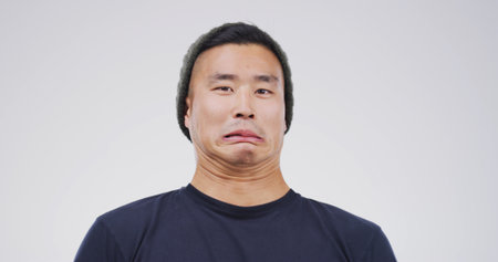 Comic, funny face and portrait with man on studio space for emotions, humor or silly joke. Comedy, emoji and unique with goofy Asian person isolated on white background for crazy or quirky reactionの写真素材