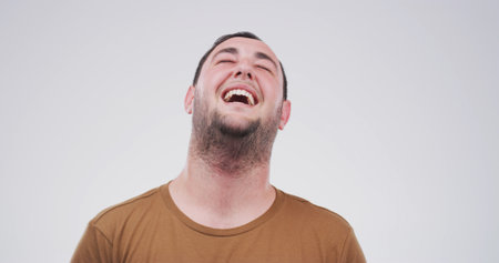 Laugh, happy and face of man in studio with funny joke, humor and comedy on white background. Emoji, confidence and isolated person with laughter for positive attitude, cheerful and joy for comicの写真素材