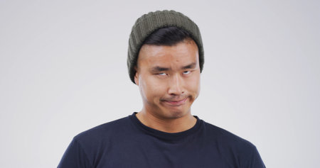 Silly, crazy and Asian man in studio with funny face for playful, comedy and humor on white...