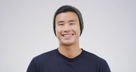 Portrait, Asian man or student with smile in studio for education, scholarship and college. Space, male academic or beanie for learning, study opportunity or university curriculum on white backgroundの写真素材